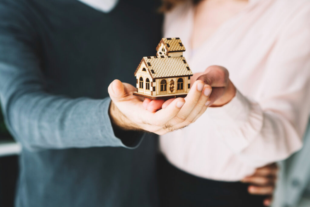 Crop couple holding toy house
