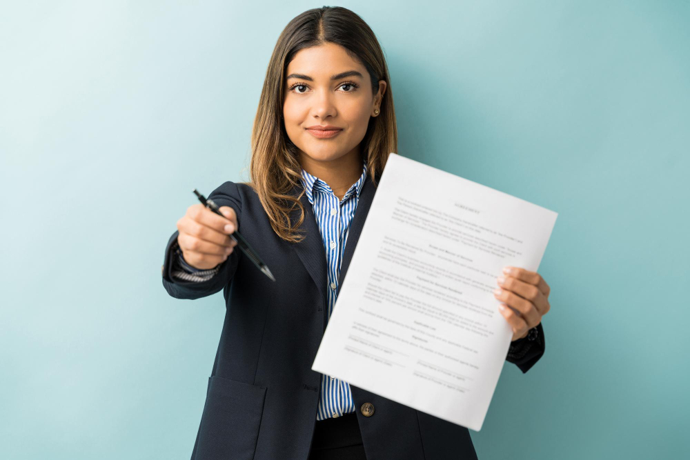 Confident young female professional with contract and pen against colored background
