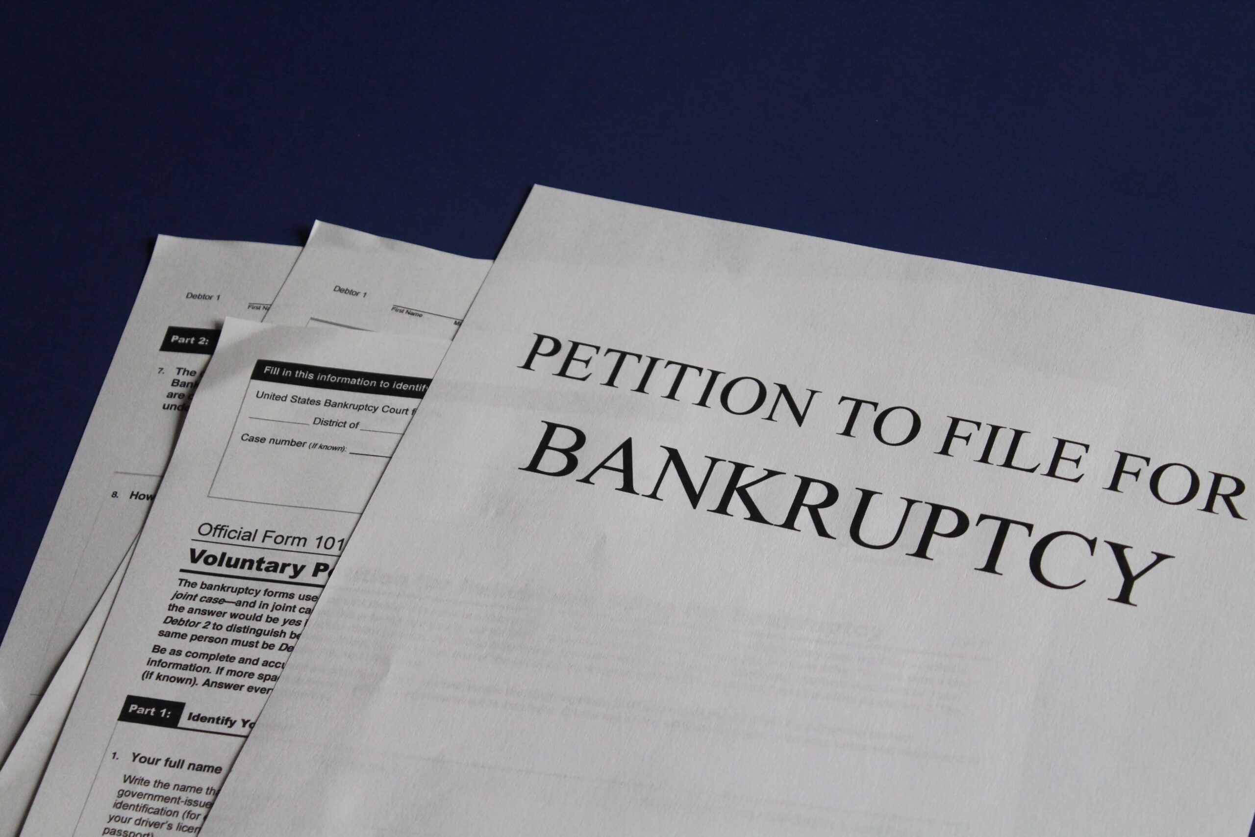 Petition to file for bankruptcy papers spread across a blue surface 