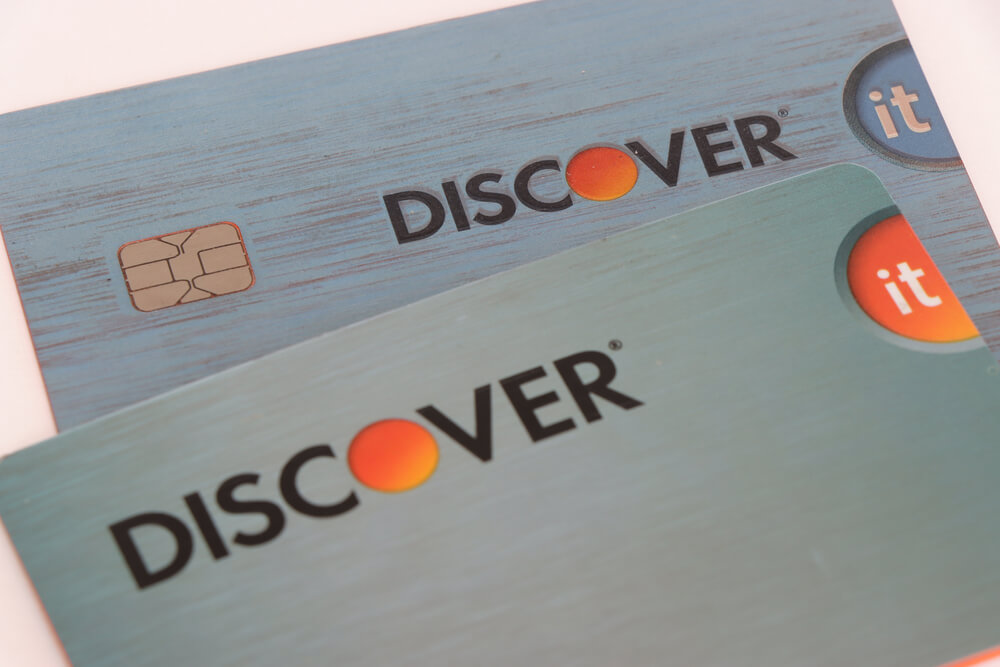 Two blue Discover cards stacked laying on a white surface 