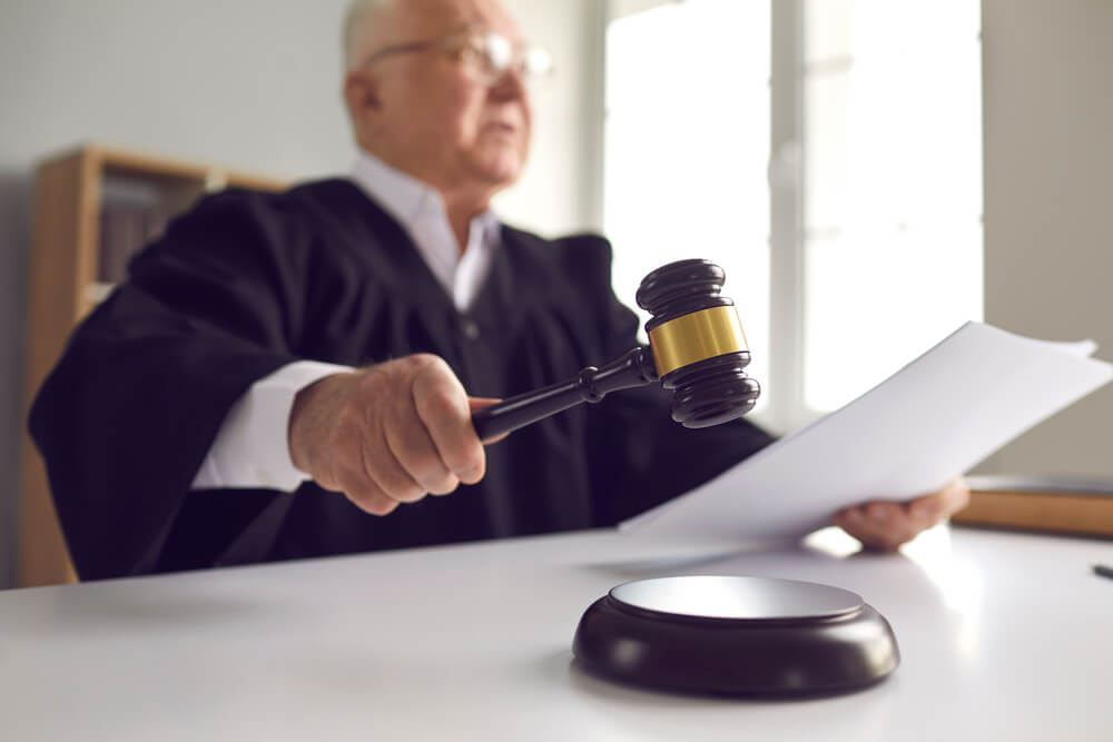 Judge holding a paper and in the process of hitting his gavel 