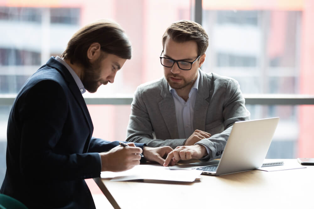 Lawyer helping a man, they are looking over documents and the lawyer is explaining something to the man