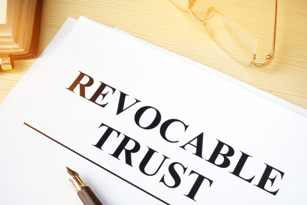 A paper stating the word Revocable Trust with pen on top of paper