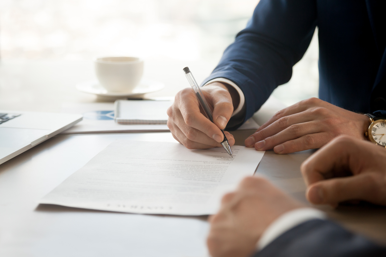 person-signing-document-in-front-of-representative