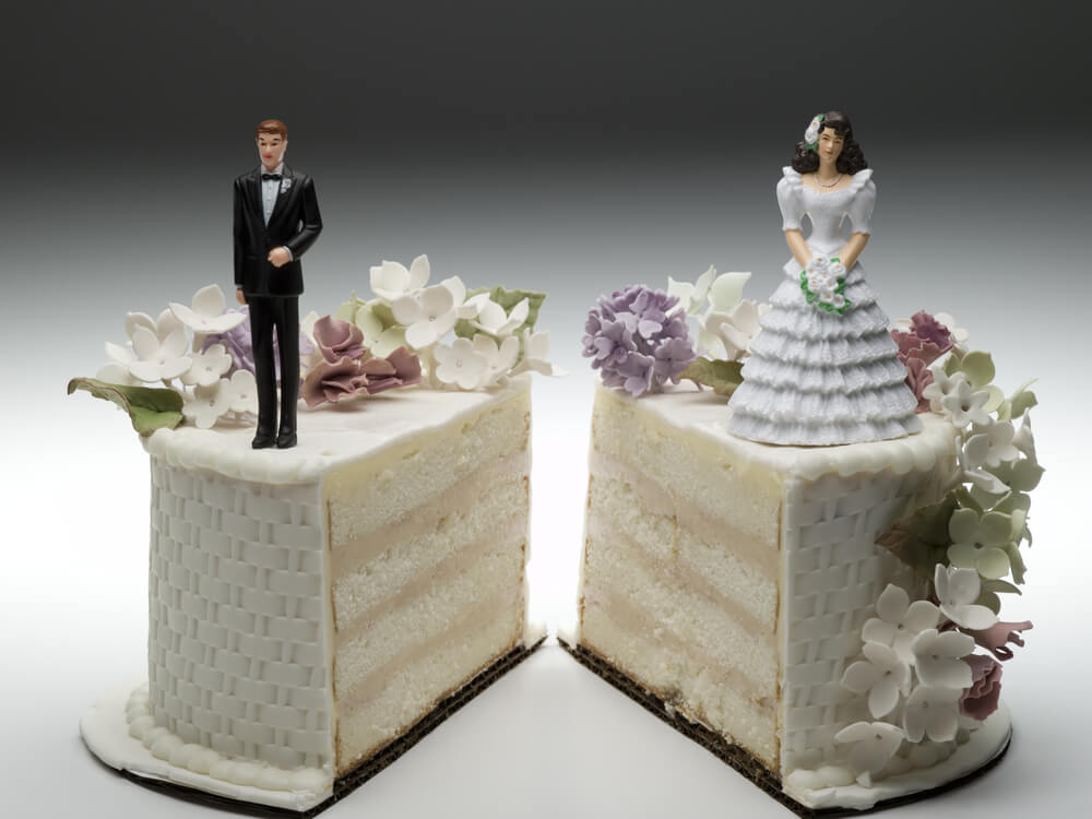 Wedding cake cut in half with a bride topper on the right and the groom topper on the left