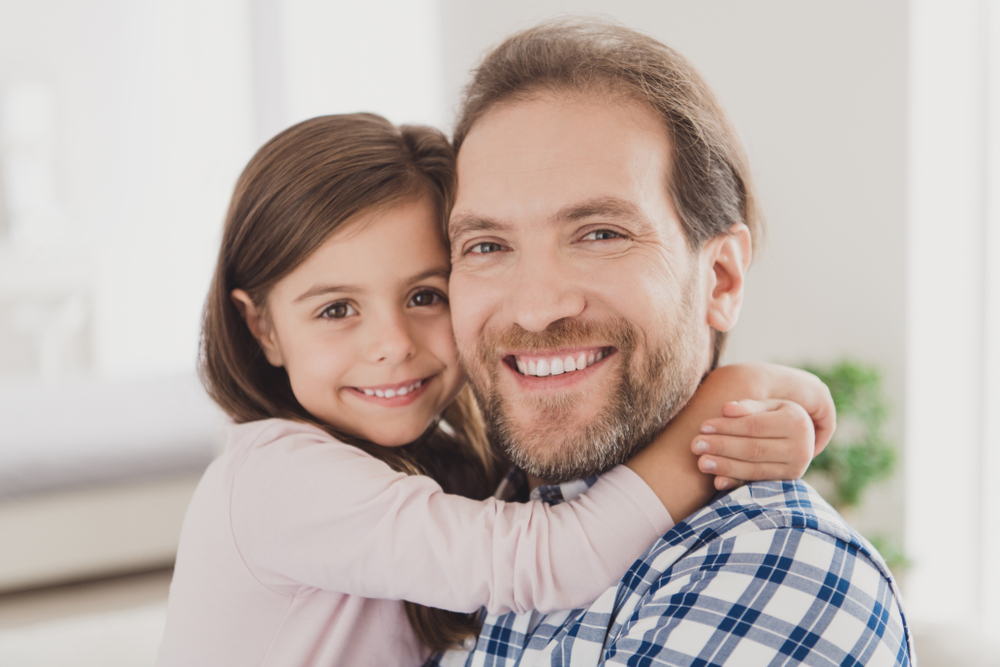 Dad hugging his daughter and both of them are smiling
