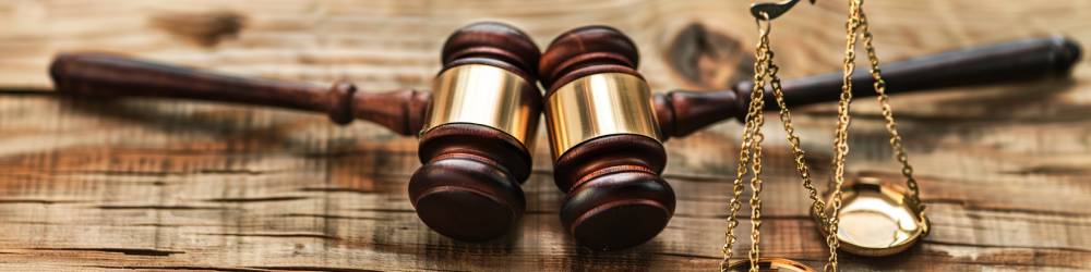 Two wooden gavels and a set of brass scales are placed on a wooden surface, reminiscent of the high-profile divorce cases frequently seen in Texas courtrooms.