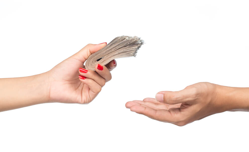A closeup of a woman giving a stack of money to a man 