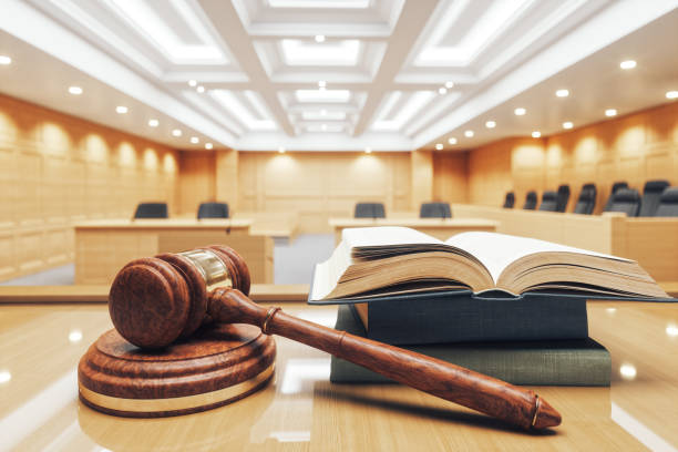 In Jenkins Court, the empty courtroom stands solemnly with a wooden gavel, an open law book, and the judge's bench illuminated under bright ceiling lights, awaiting the next session with court receivers.