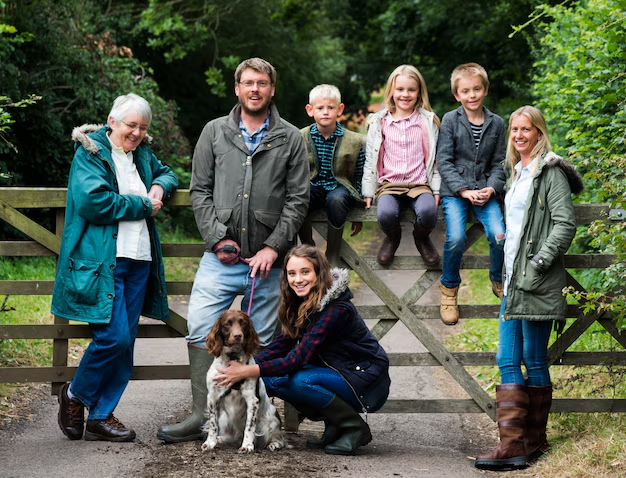 A family of seven and their dog pose by a wooden gate in a lush, green outdoor setting, thoughtfully reflecting on what estate planning documents they might need for peace of mind.