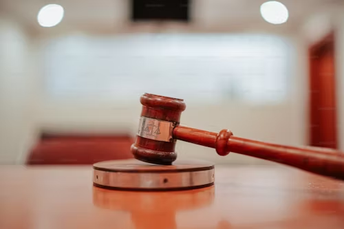 A wooden gavel, symbolizing justice, rests on a circular base in a courtroom setting with blurred background lighting, as the buzz surrounding the Ally Bank lawsuit fills the air.