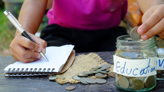 A child is diligently saving coins to fund their education.
