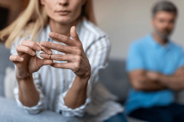 A man and woman sitting on a couch with their hands discreetly tucked in their pockets.