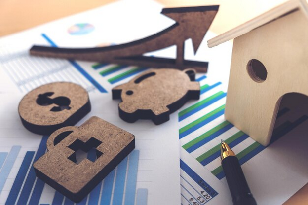 A wooden house and a pen on top of a piece of paper.