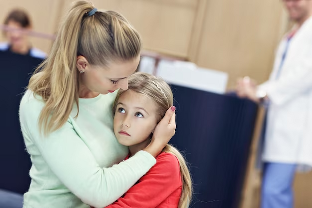 A young girl is hugging her mother in a doctor's office.