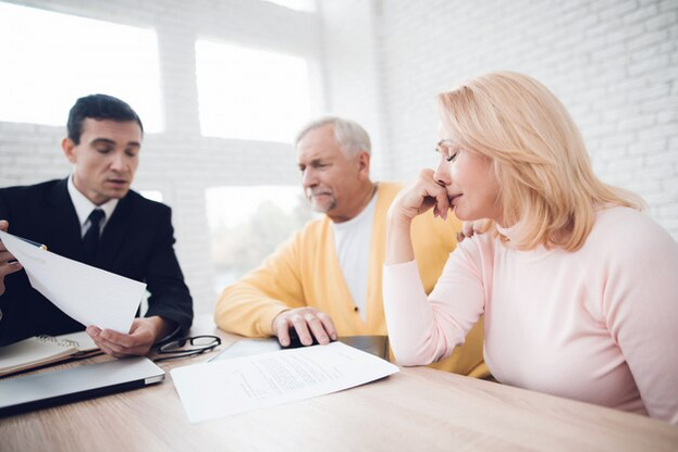 Three people sitting at a table looking at papers.