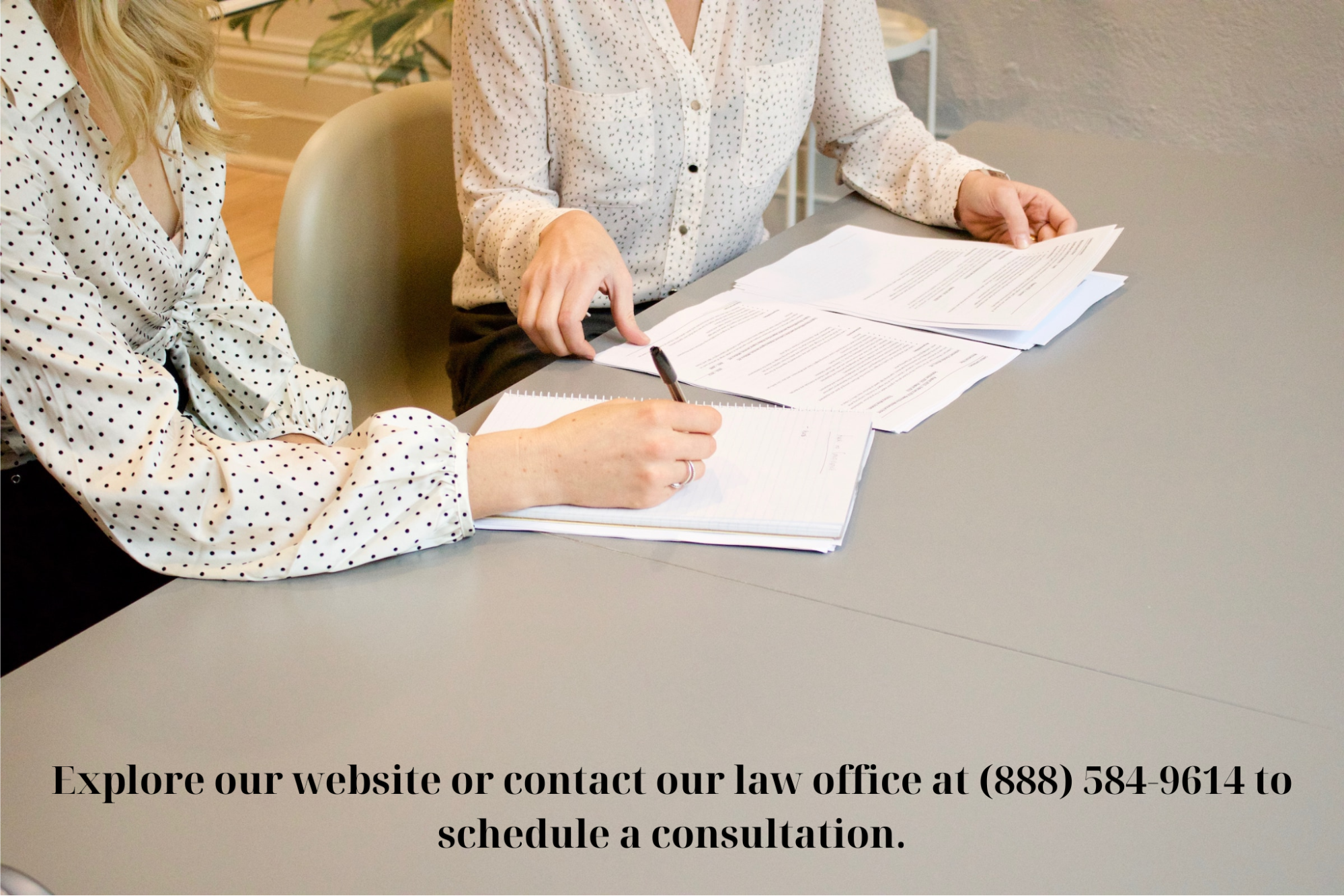 Two women sitting at a desk signing papers.