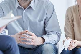 A man and woman sitting on a couch talking to a therapist about their personal finances during divorce proceedings.