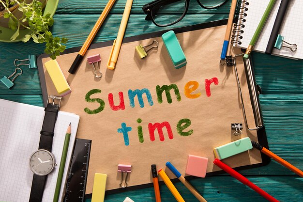 The word summer time is written on a piece of paper on a wooden table.