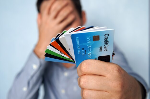 A man holding up a bunch of credit cards seeks the assistance of a Credit Card Debt Lawyer.