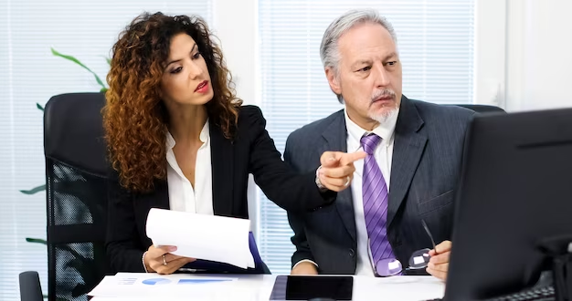 Two business people sitting at a desk going over paperwork
