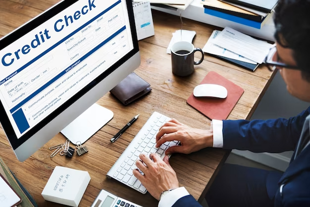 A man working on a computer with a credit check on the screen.