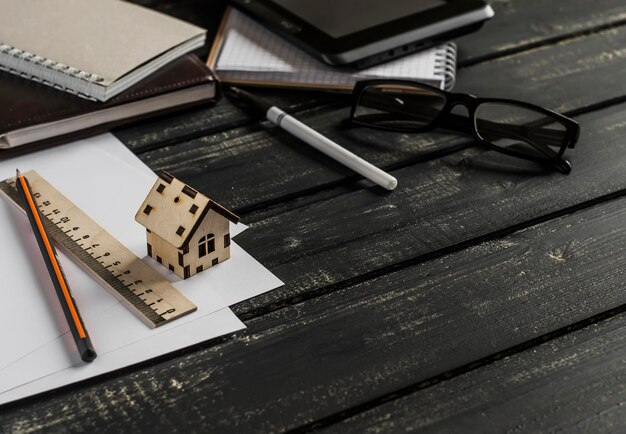 A house model on a wooden table with pens, pencils and a ruler for Contested Divorce in Texas.