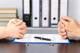 Two people signing a marriage contract at a desk, wondering if they can empty their personal bank account before divorce.
