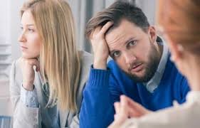 A man and woman sitting at a table in a meeting, discussing the possibility of emptying their personal bank accounts before divorce.