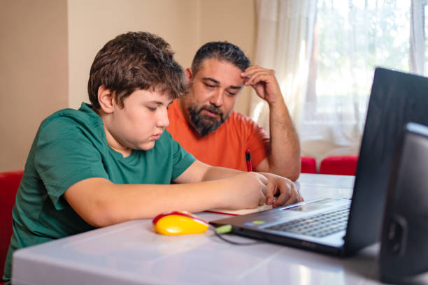 angry father Helps Stressed Teenage son With Homework at home during the day while sitting around table in front of laptop, Parent and Child Both Have a Learning Disorder
