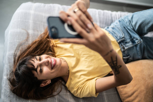 Young woman using the mobile phone in the bed at home
