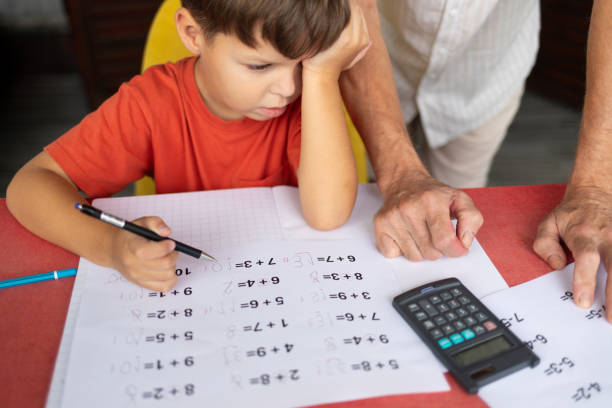 A six-year-old boy with dysgraphia and dyscalculia struggles with his math homework, staring at a worksheet with many corrections. His father stands nearby, leaning his hands on the table, trying to help his son with the assignment. The child looks frustrated and tired, rubbing his eyes in confusion and exhaustion.