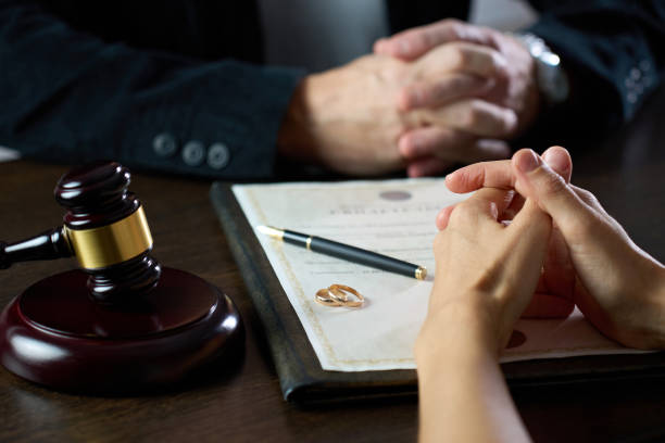 Couple sitting at table with divorce document, close-up, selective focus. Signing divorce agreement