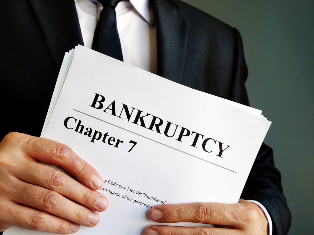Business man holding a stack of papers and the top paper says bankruptcy chapter 7