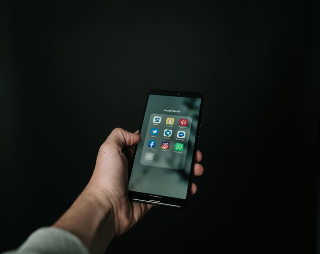 Man holding phone showing social media icons