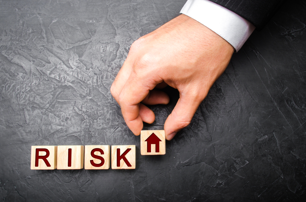The realtor's hand stretches a cube with a house pattern to the word risk. The concept of risk, loss of real estate. Property insurance. Loans secured by home, apartment. Financial risks, litigation. abstract of judgement texas