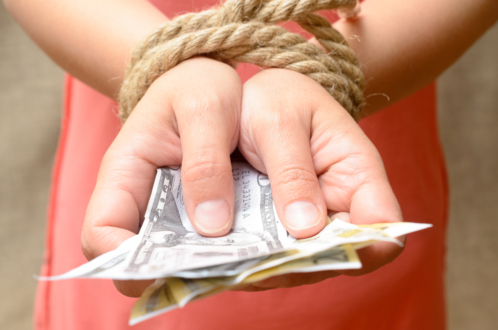 Women's hands tied with a rope and holding money. Credit bondage.