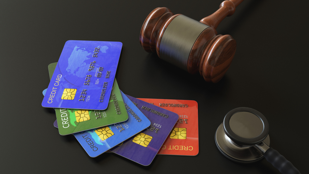 credit card , gavel and stethoscope on black floor, business or law concept