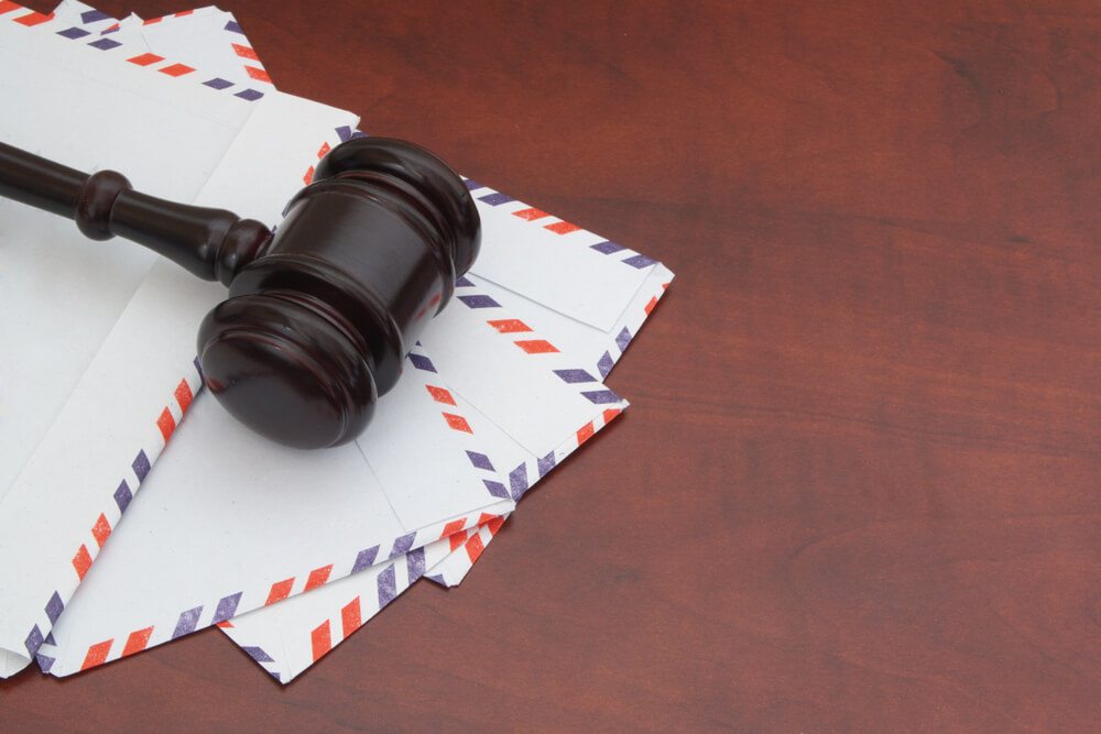 Many empty envelopes sitting on a wooden desk with a gavel on top of them 
