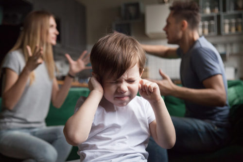 Frustrated kid son puts fingers in ears not listening to noisy parents arguing, stressed preschool boy suffering from mom and dad fighting shouting, family conflicts negative impact on child concept