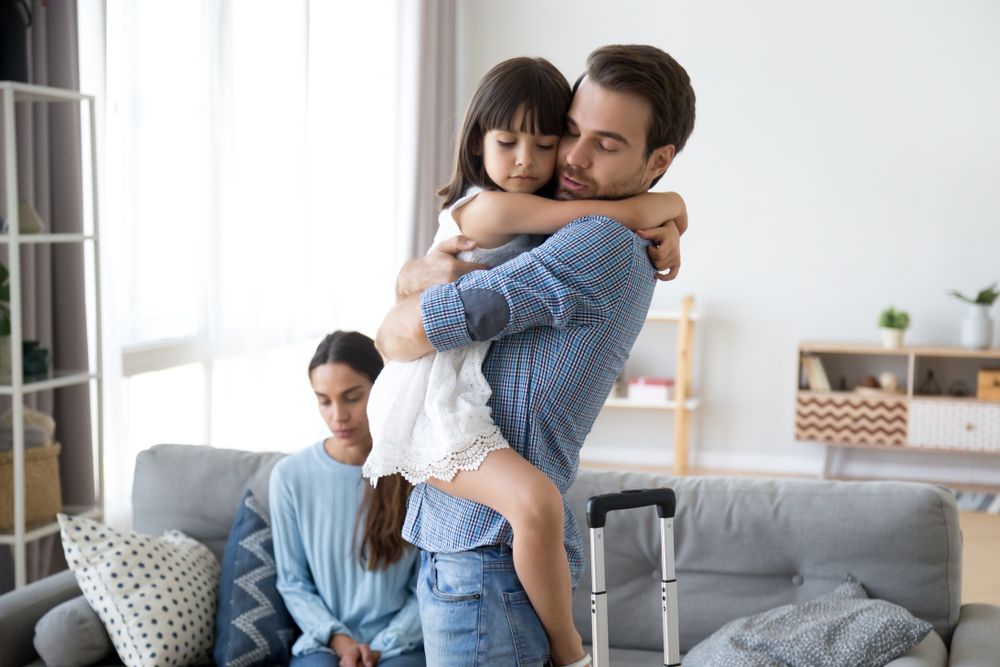 Sad little girl upset by father leaving embracing dad, depressed child saying goodbye hugging daddy going away, kid and parents divorcing breaking up, family separation, shared custody concept in the article material change in circumstances