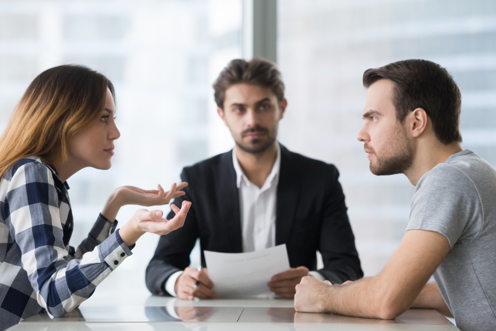 Annoyed unhappy married couple arguing in lawyers office get divorced, angry family spouses split up having disagreement disputing about breaking up and divorce settlement, legal separation concept