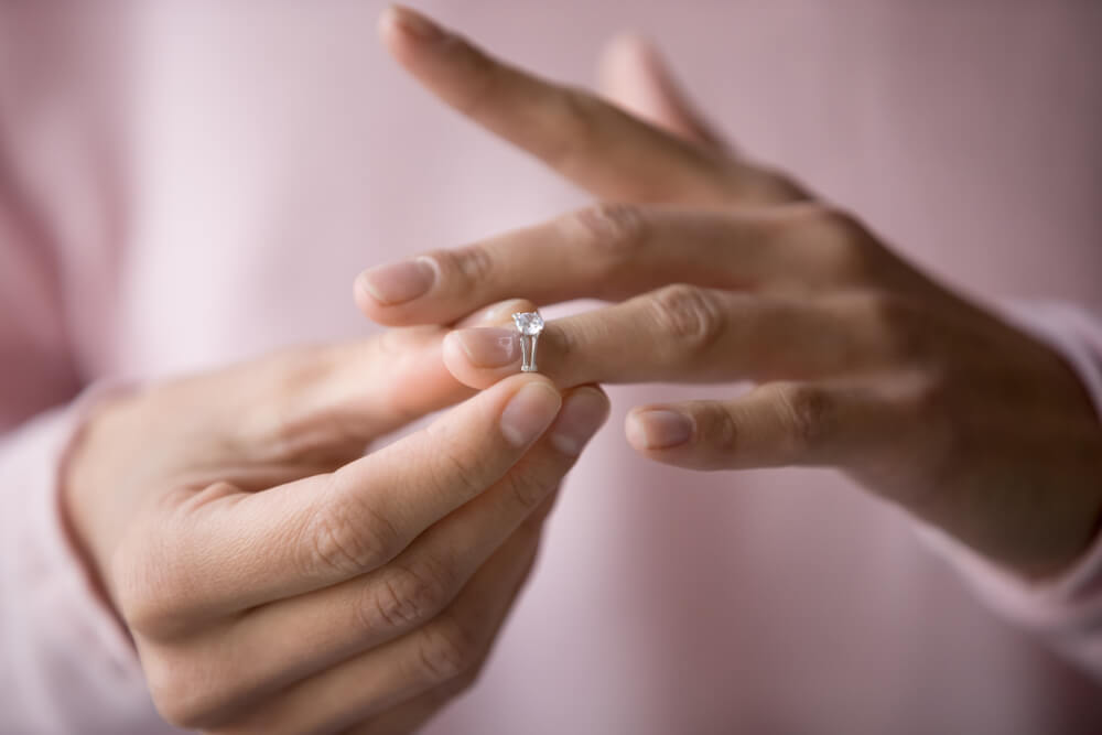 A close up image of a woman taking off her wedding ring 