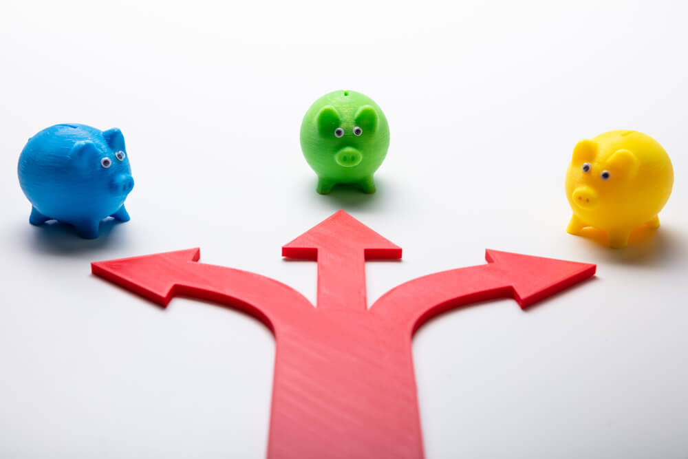 An arrow that splits into three and is pointing at three different piggy banks, a blue one, a green one, and a yellow one