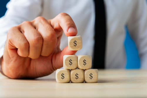 Finances in divorce concept. Wife and husband can not make settlement holding piggy bank sitting at table looking at each other with hatred, future earnings divorce