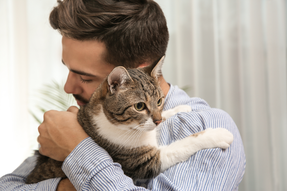 Happy man with cat at home. Friendly pet