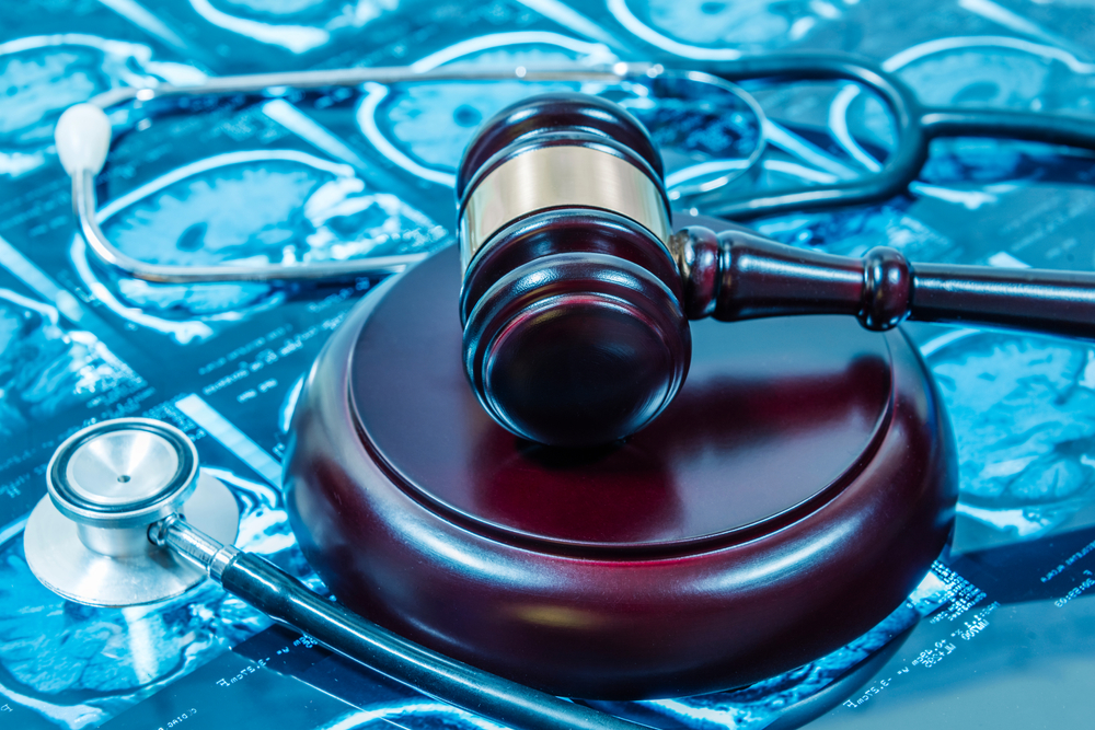A judge's gavel and a stethoscope rest on brain scan images, symbolizing the intersection of law and medicine..