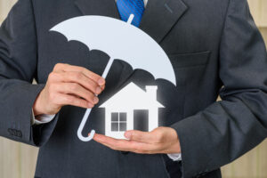 Protection from mortgage foreclosure and land contract forfeiture, business concept : Businessman protects a home or a house, depict protecting a borrower or buyer from failing to pay money to lender