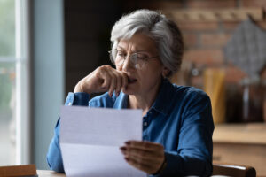 Ugly news. Distressed old age hispanic female check documents at home office read debt bankruptcy information in financial report. Upset stressed older latin woman get bad surprise in official letter