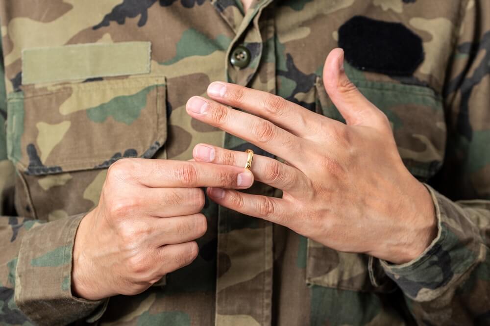 A close up of a military man taking off his wedding ring 